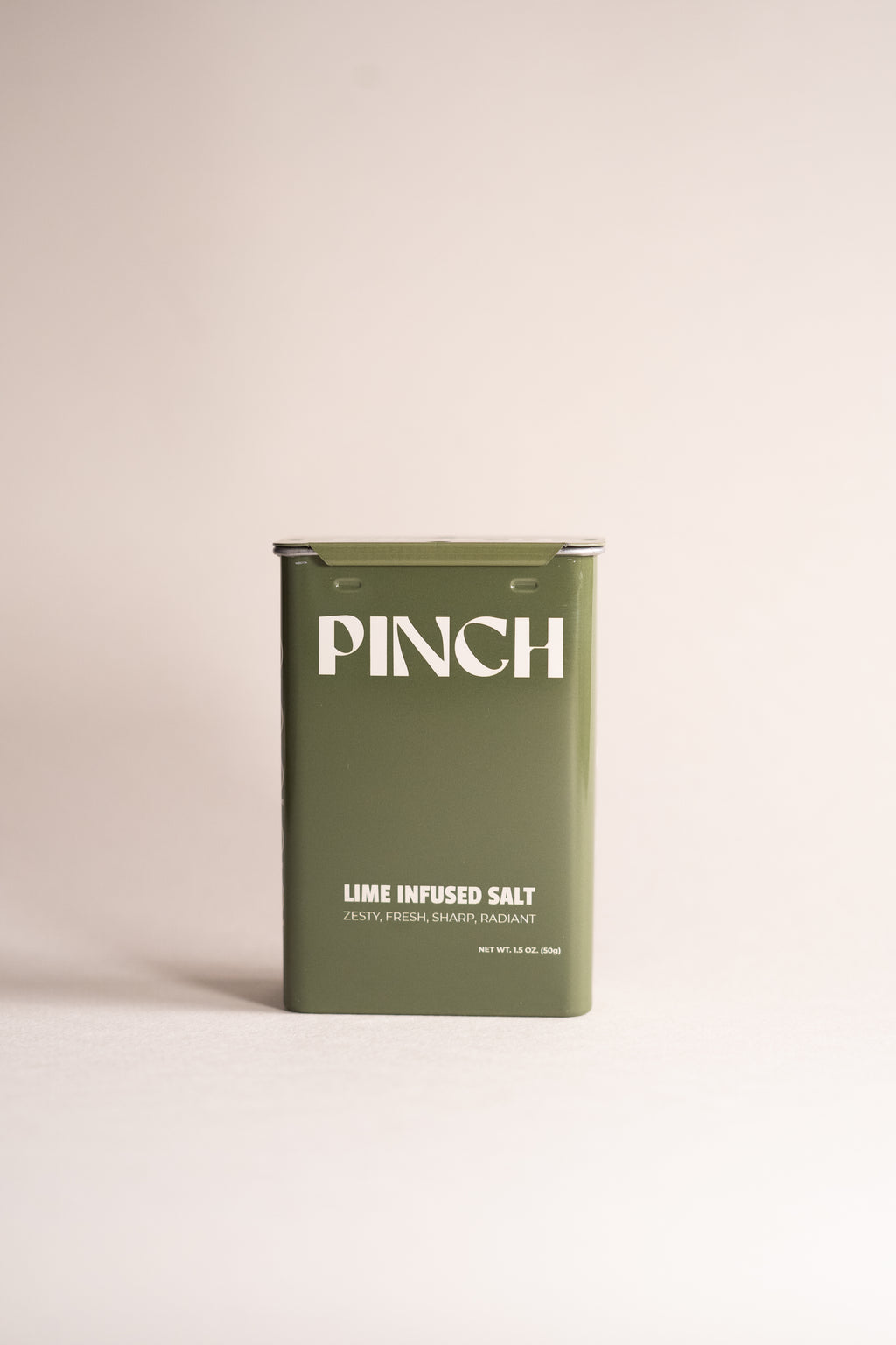 Green container of 'PINCH' lime infused salt on a beige background