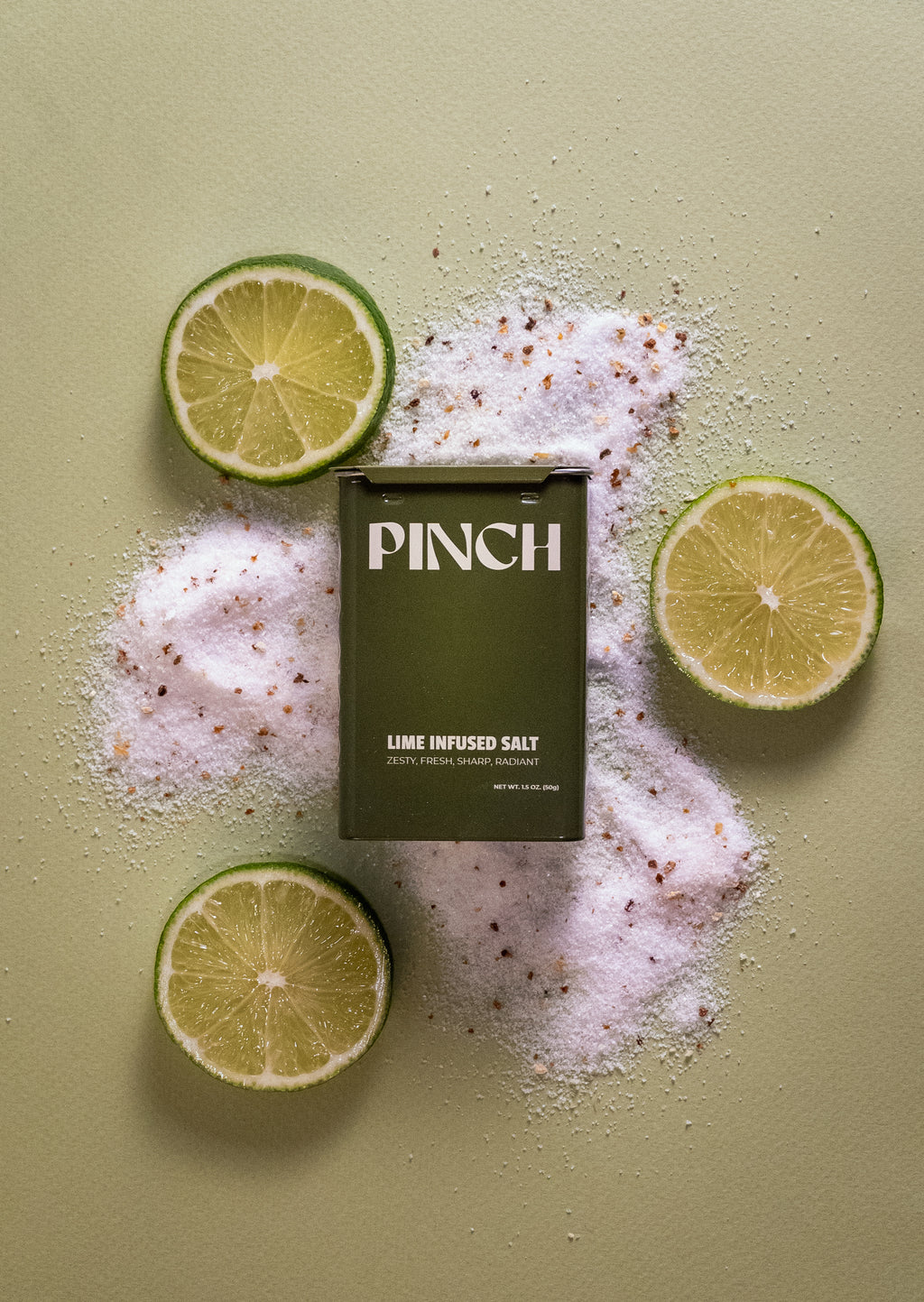 PINCH lime infused salt packaging surrounded by lime slices on a light green background