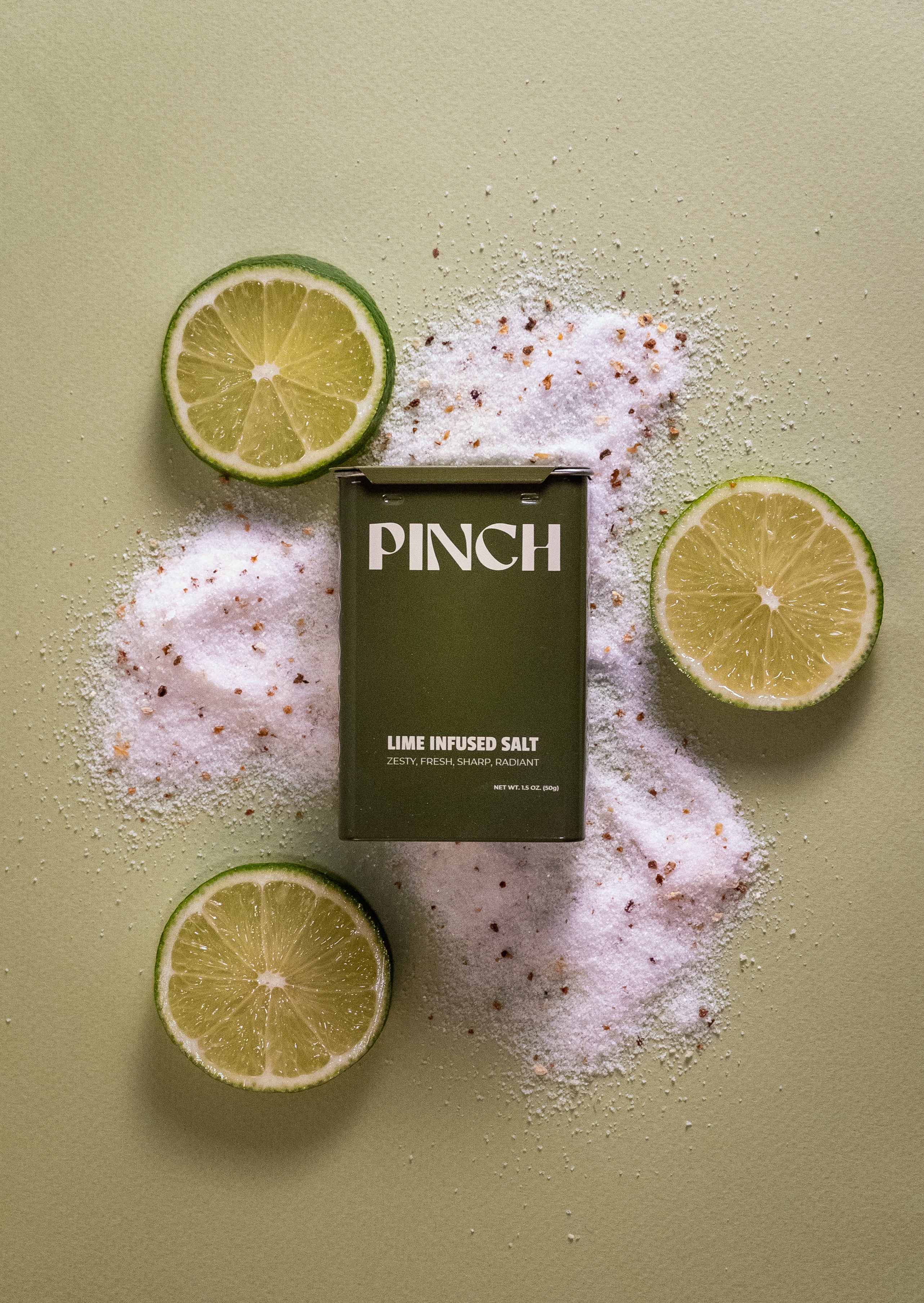 PINCH lime infused salt packaging surrounded by lime slices on a light green background