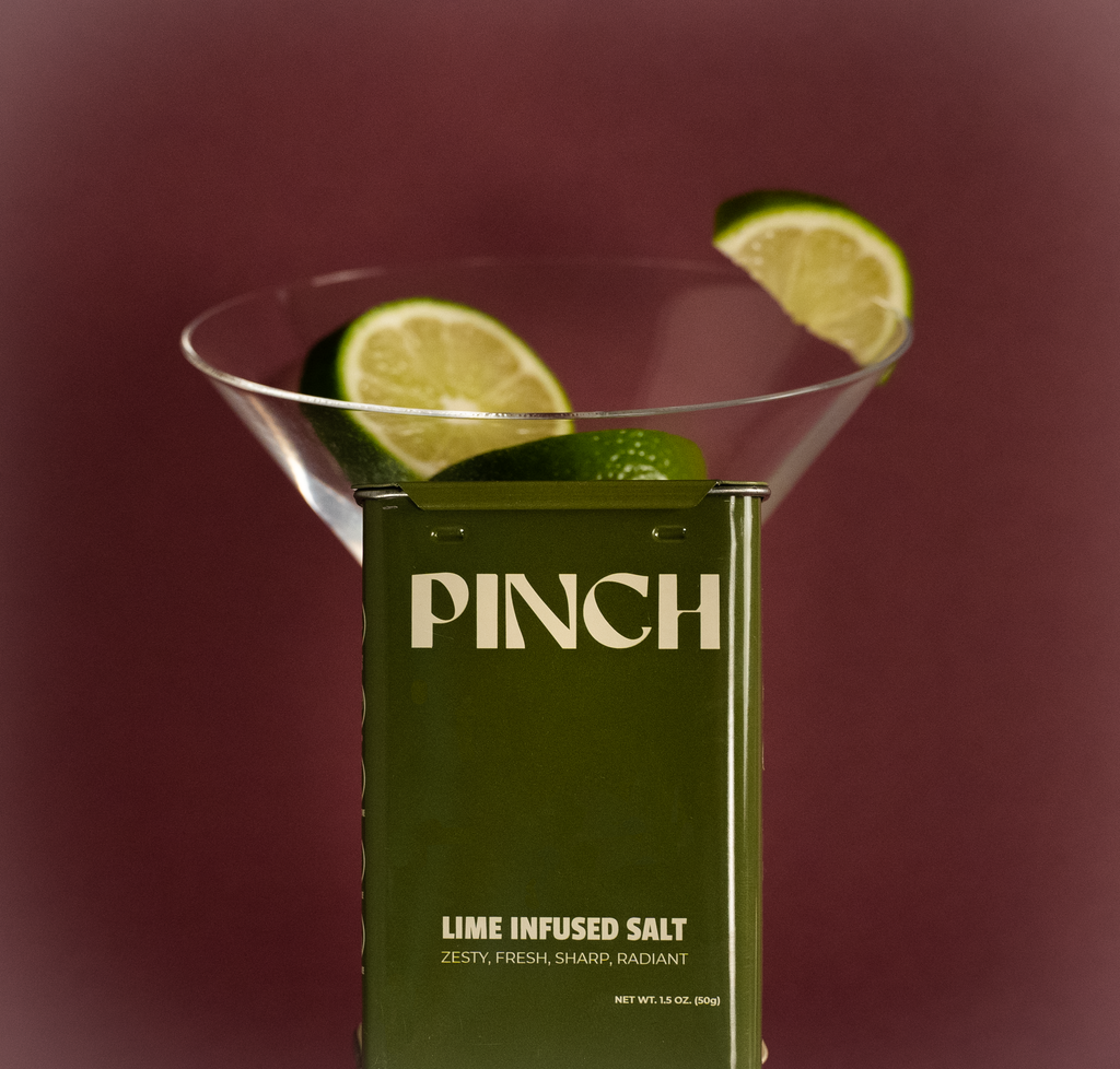 Pinch lime infused salt packaging with a martini glass and lime slices on a red background